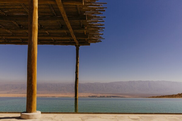 A wooden structure with a view of a calm body of water and distant mountains.