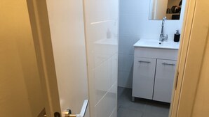 Baño con lavamanos, espejo y mueble blanco.