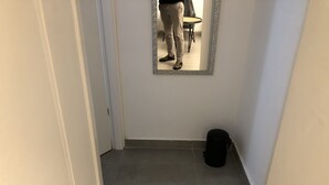 A narrow hallway with a tiled floor, a mirror on the wall, and a black bag on the floor. - Arnon-6 - Adults Only (Tel Aviv)