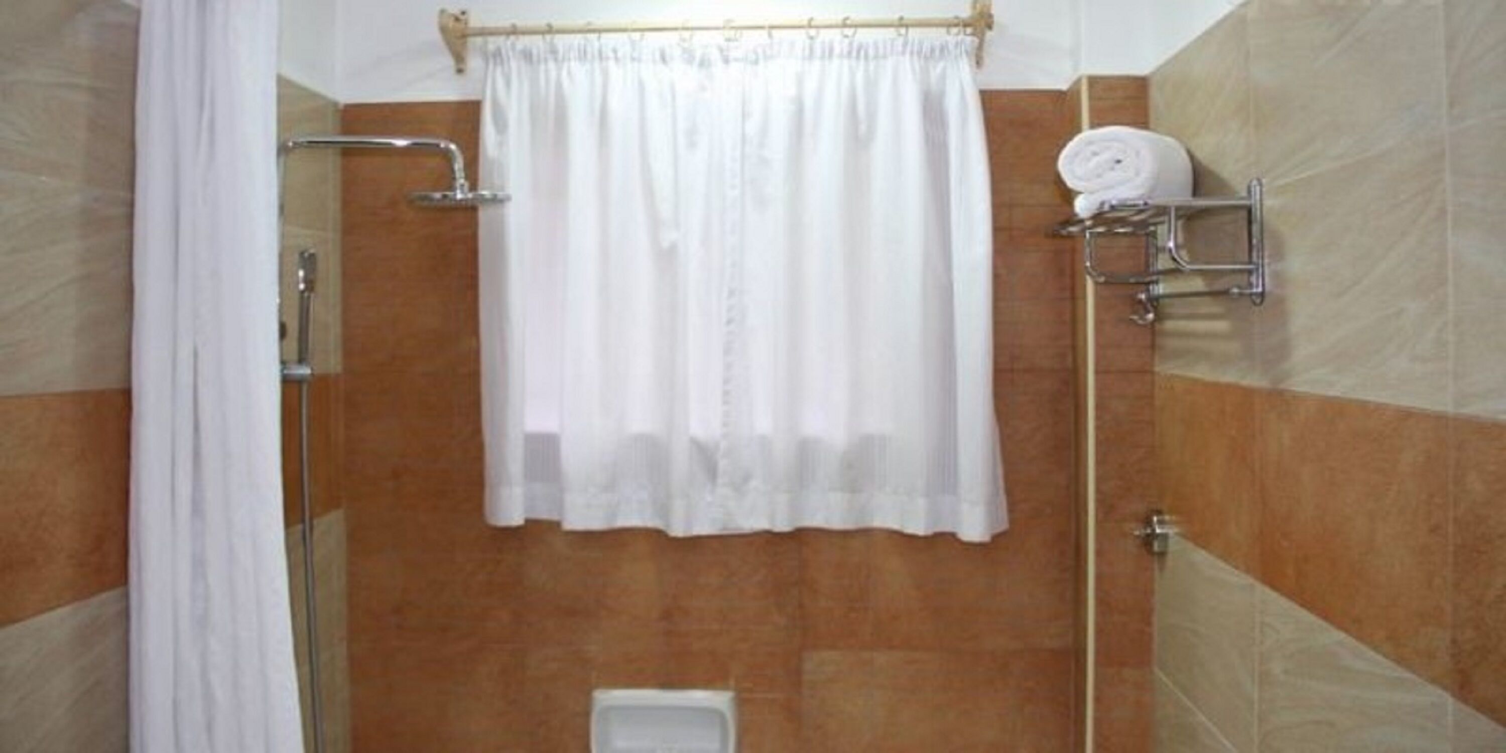 A bathroom with a shower, a toilet, and a towel rack with towels.