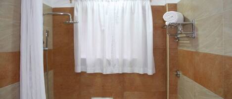 Un baño con ducha, inodoro y toallero con toallas.