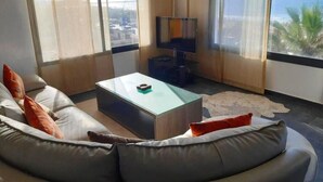 Een moderne woonkamer met een gebogen bank, een glazen salontafel en een flatscreen televisie.