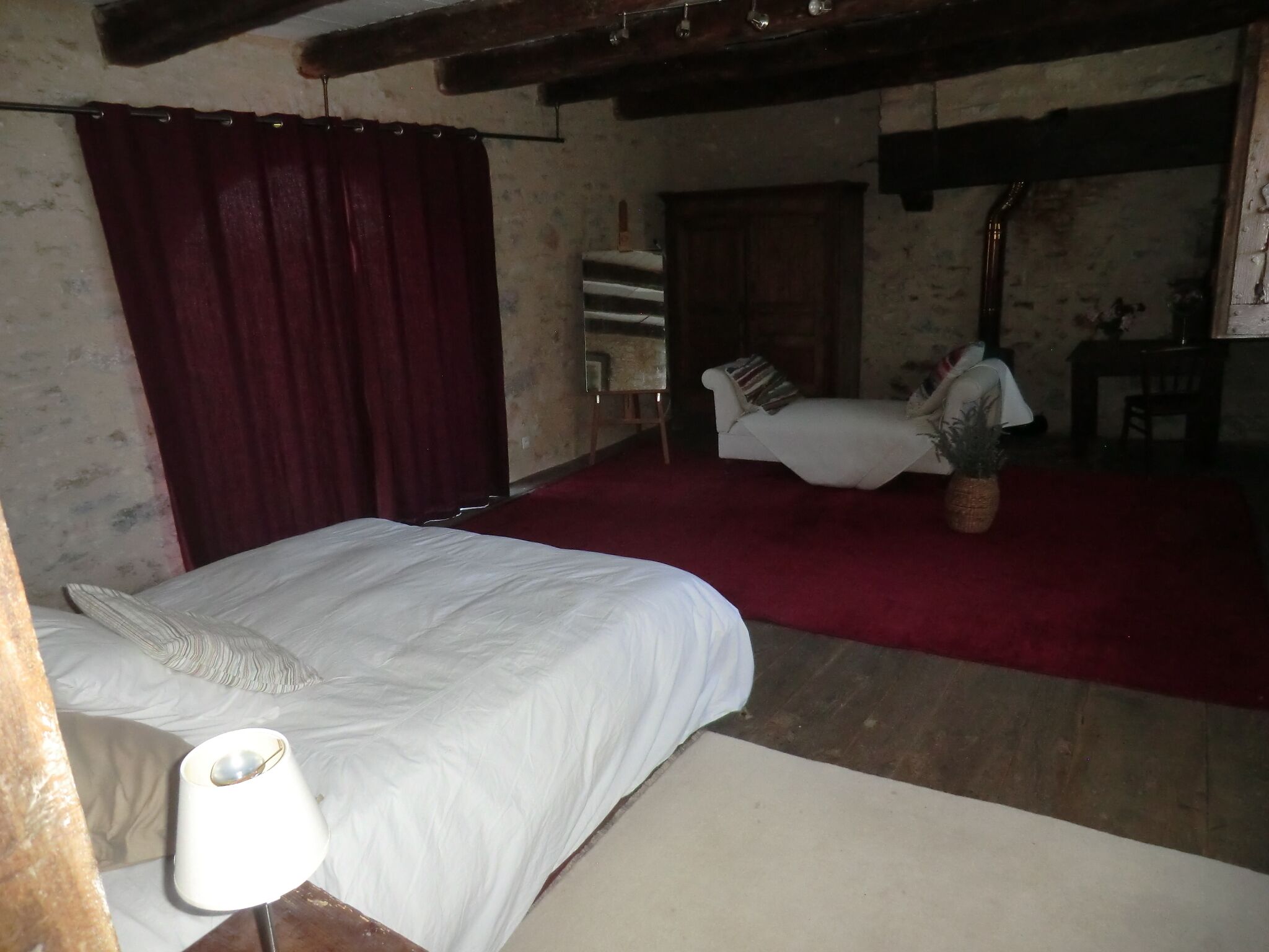 Un dormitorio con cama, una silla, una mesita y un espejo.