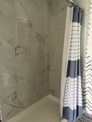 Een badkamer met marmeren tegels en een douchegordijn met strepen.