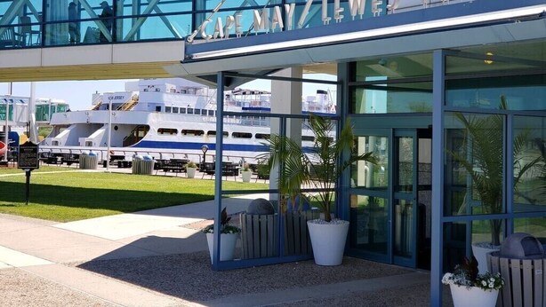 Ein Fährterminal mit moderner Glasfassade und einem Schild mit der Aufschrift 'Cape May Lewes Ferry'.