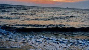 Ein Strand mit Wellen und einem Sonnenuntergang.