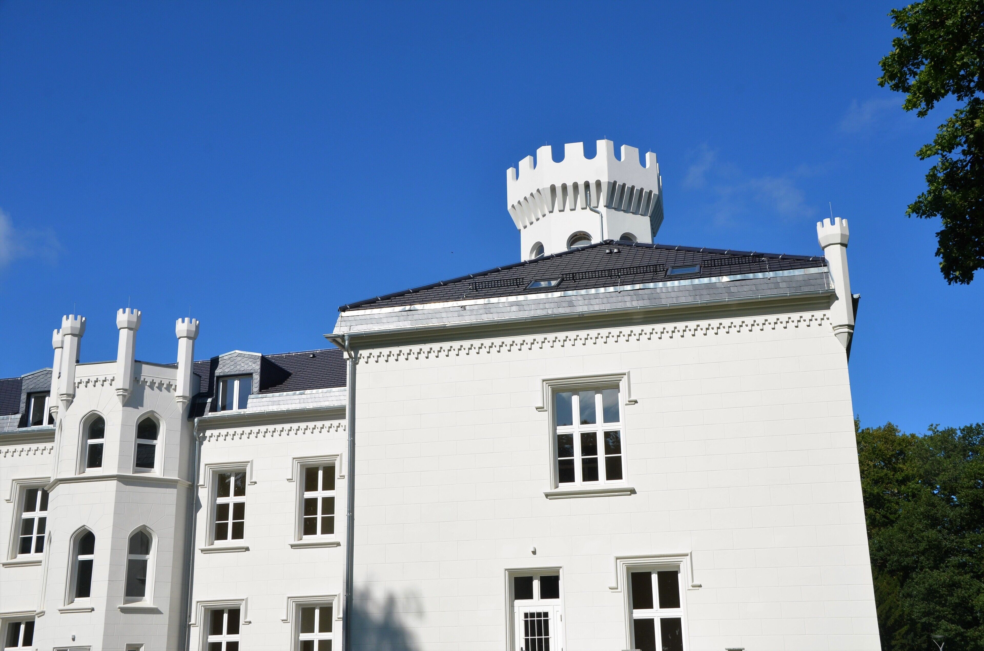 Un bâtiment blanc doté d’une tourelle et de plusieurs cheminées.