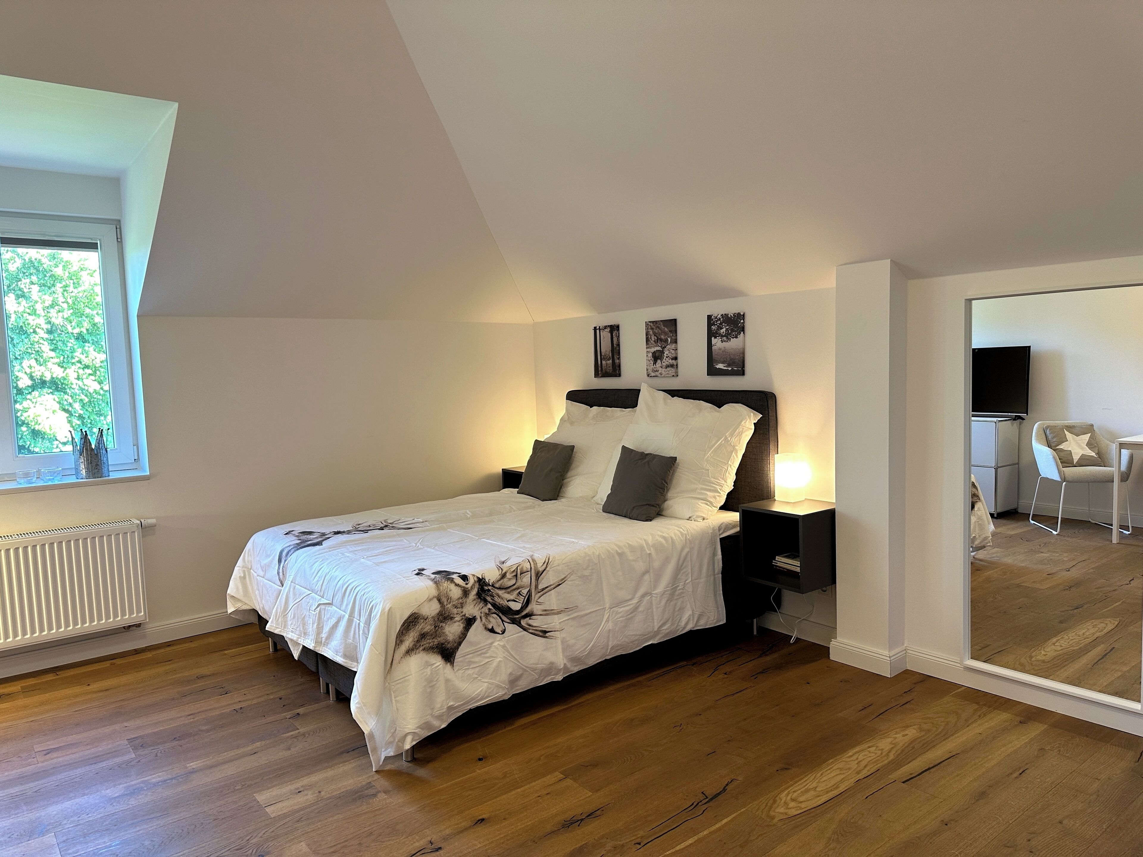A bedroom with a bed, a nightstand, a chair, and a TV.