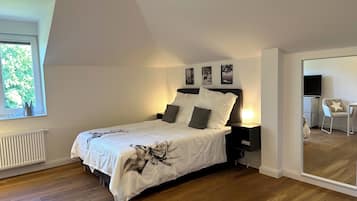 A bedroom with a bed, a nightstand, a chair, and a TV.