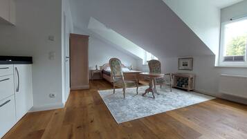 A bedroom with a bed, a nightstand, a chair, a table, and a window.
