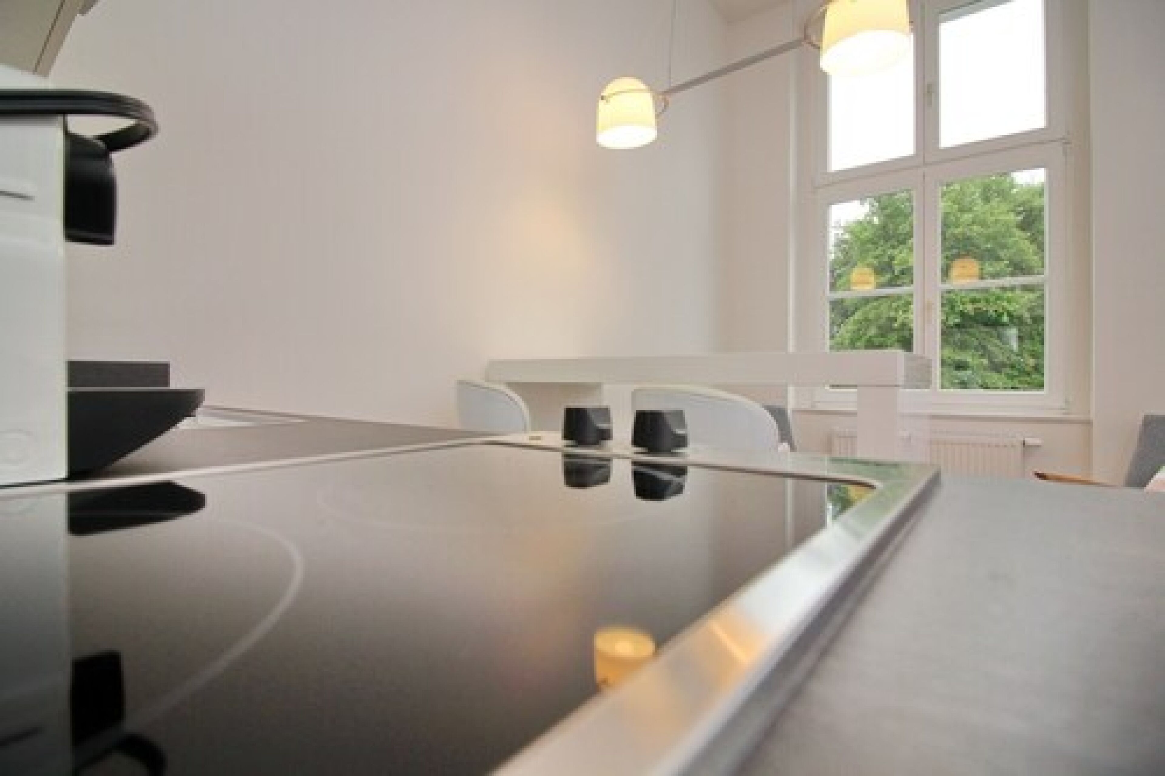 A modern kitchen with a sleek countertop, a built-in oven, and a window providing natural light.