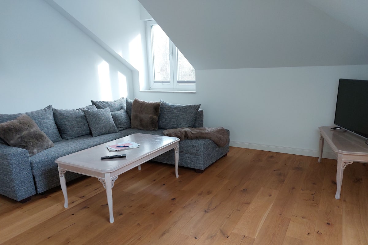 A living room with a grey sofa, a white coffee table, and a wooden floor.