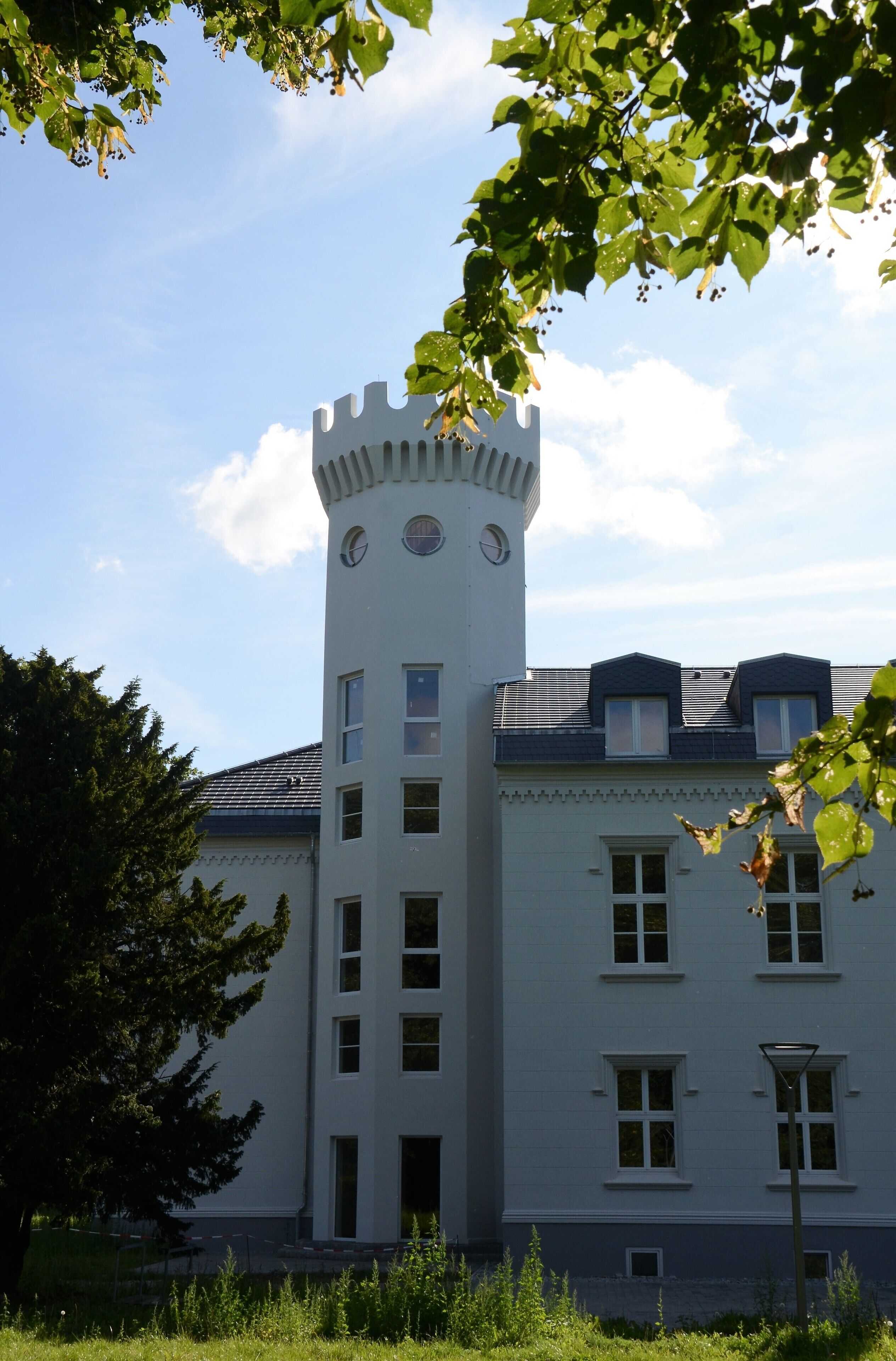 Un bâtiment blanc doté d’une tour et de nombreuses fenêtres.