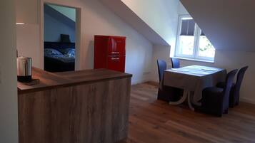 Una cocina compacta con encimera de madera, un refrigerador rojo y una zona de comedor con mesa y sillas.