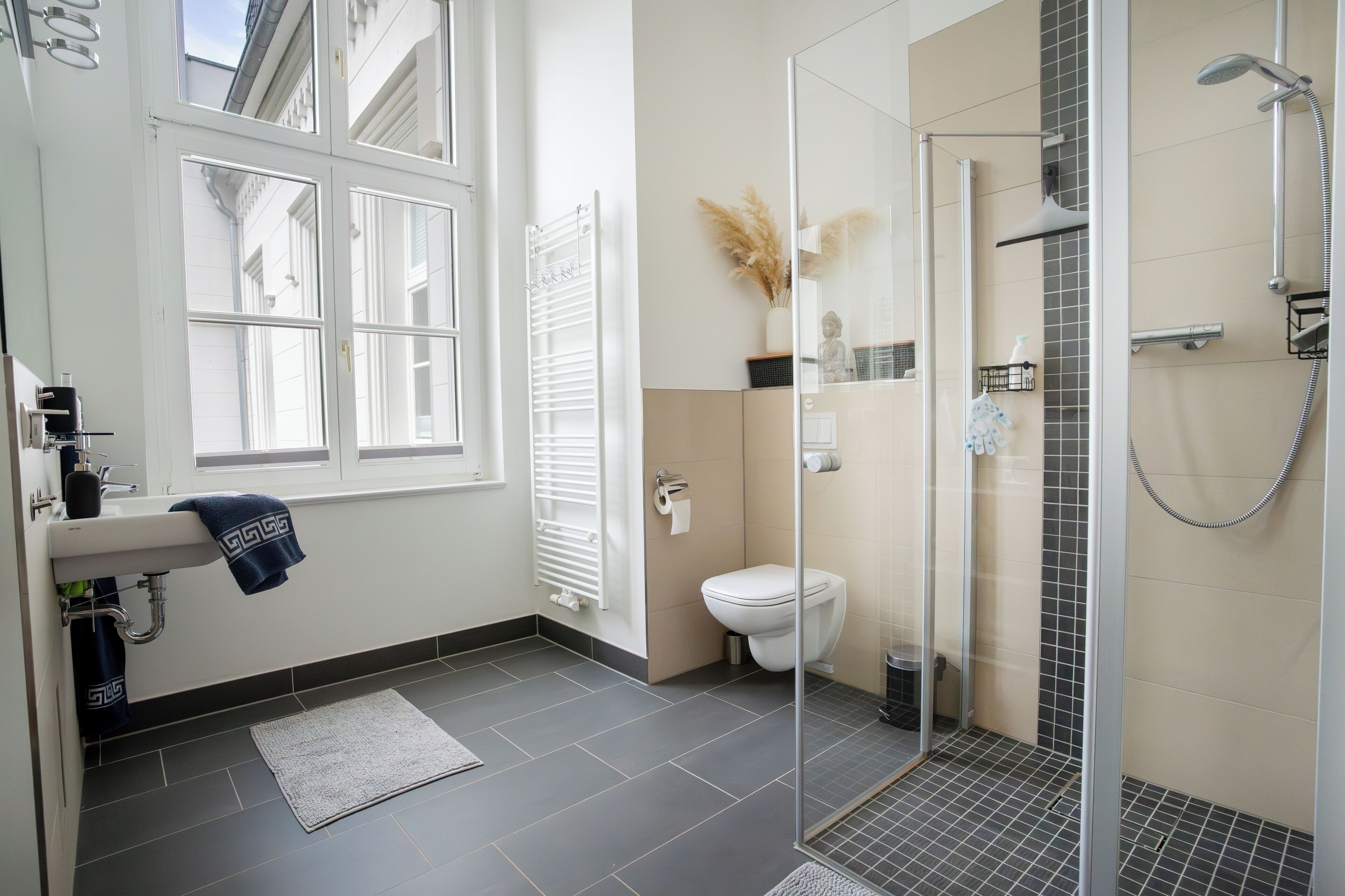 Un baño moderno con inodoro, ducha y zona de ducha con mampara de vidrio.