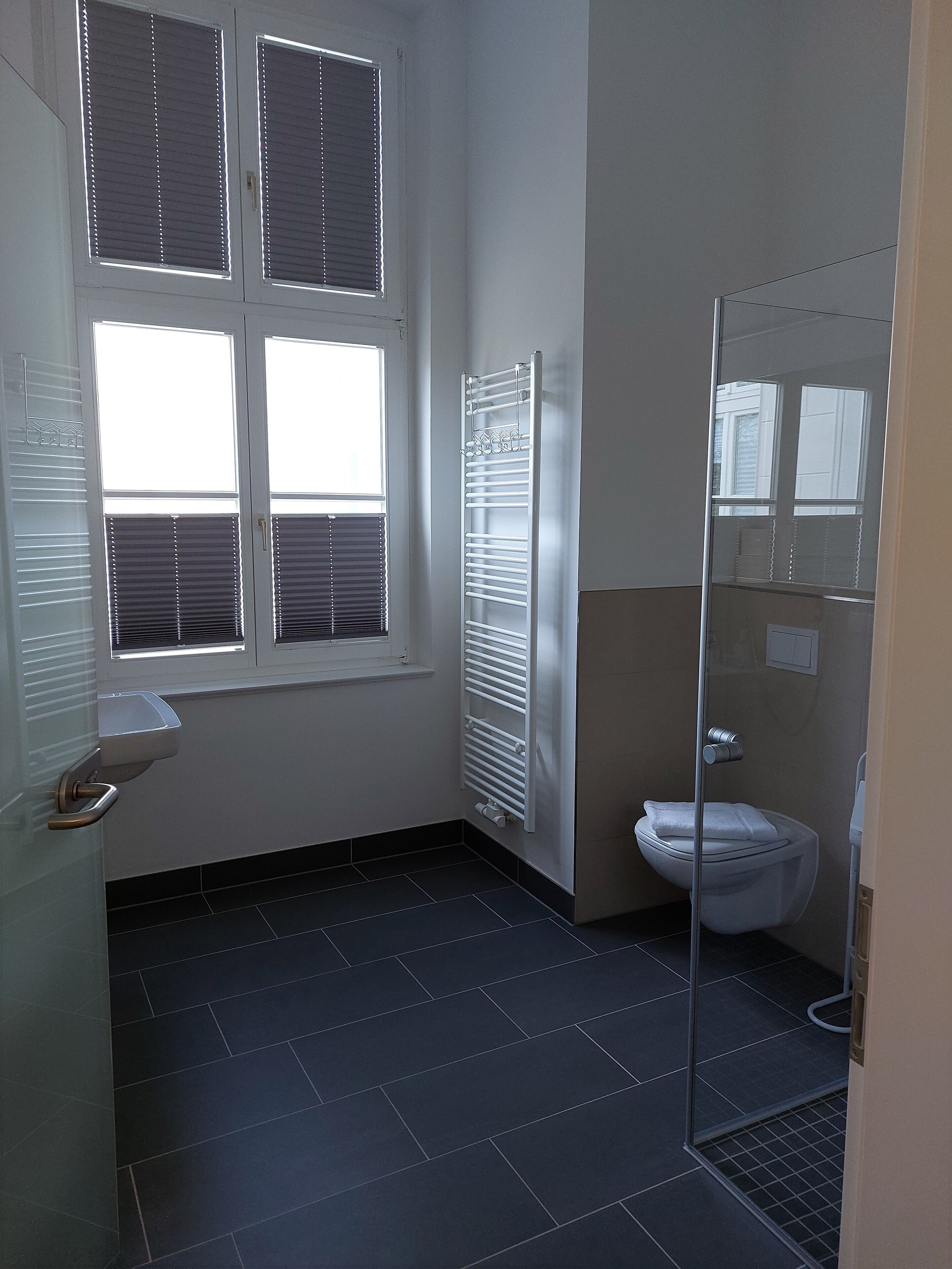Un bagno con il water, una doccia e una finestra con persiane.