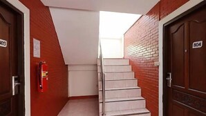 Un passadís amb una escala que condueix a una habitació lluminosa, parets de maó vermell i dues portes amb la inscripció 803 i 804.