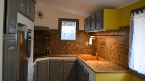 Una cocina con armarios grises, salpicadero de azulejos y una ventana con cortinas.