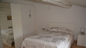 Un dormitorio con una cama, dos mesitas de noche, un tocador, un espejo y una puerta.
