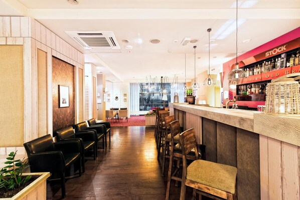 A bar area with a counter, chairs, and a seating area with a view of the bar. - Hotel Victoria (Lublin)