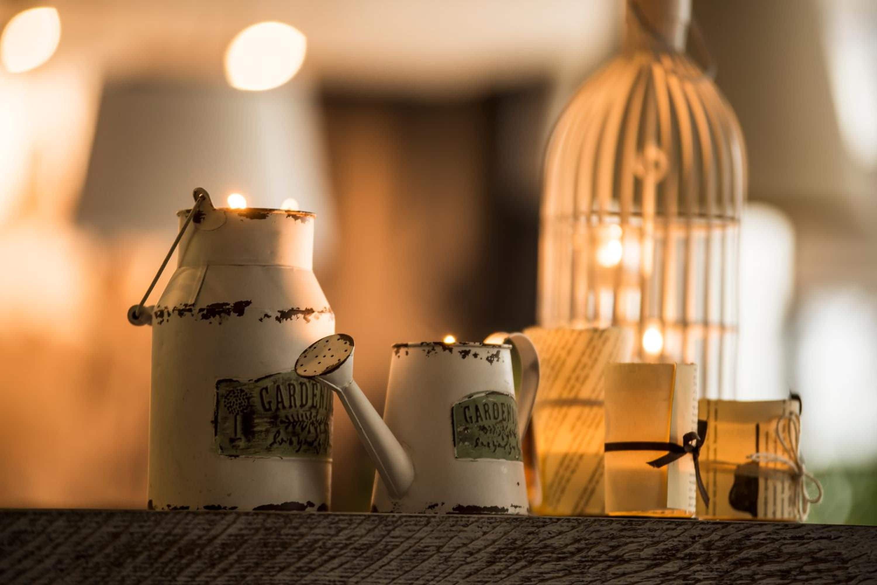 A candle holder, a candle, and a birdcage with lights, all on a textured surface.