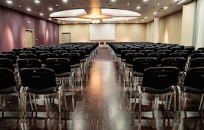 A conference room with rows of chairs facing a large screen at the front.