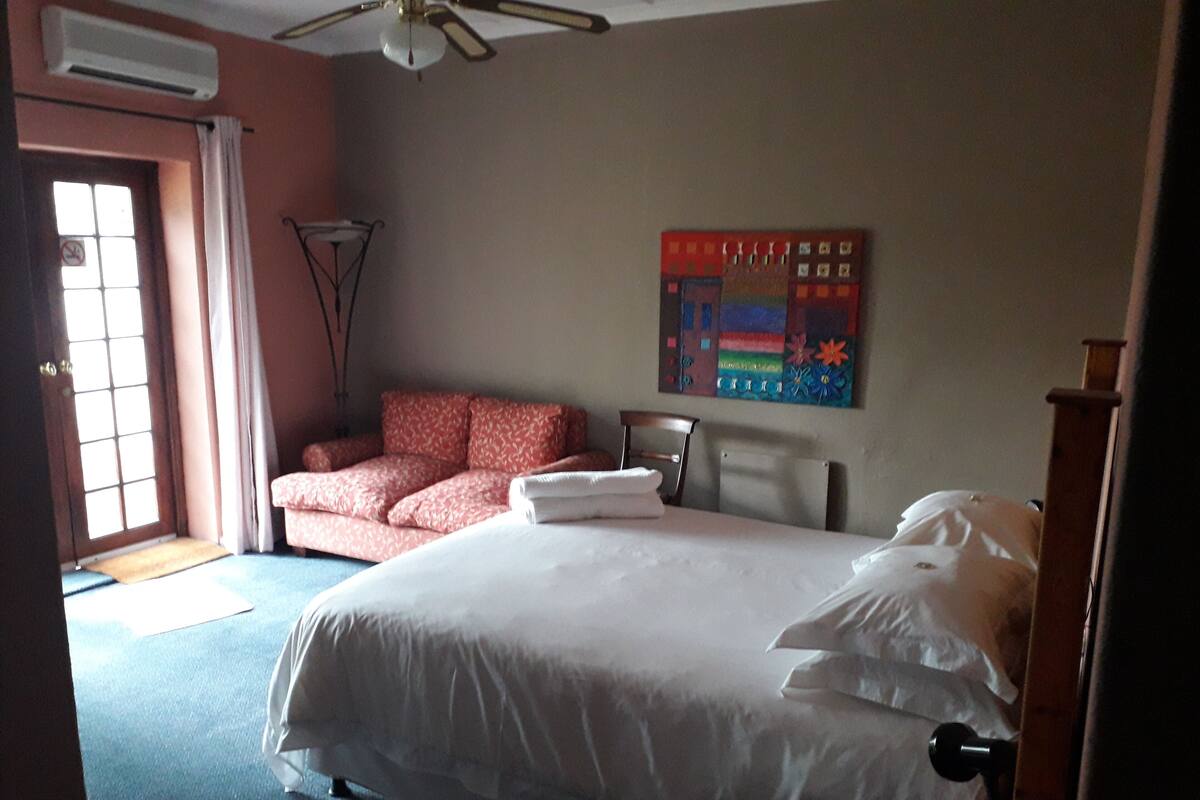 Ein Hotelzimmer mit Bett, Sofa, einem Bild an der Wand und Deckenventilator.