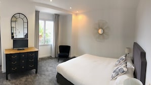 A bedroom with a bed, a dresser, a chair, a mirror, and a window with curtains. - Hotel Santa Lucia (Saint-Raphael)