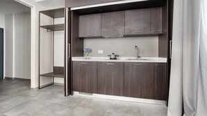 A modern kitchen with dark wood cabinets, a white countertop, and a stainless steel sink. - JOIVY Spadari (Milan)