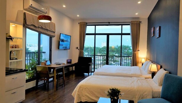 Une chambre d’hôtel avec deux lits, un bureau, une chaise, une petite table et un balcon avec vue.