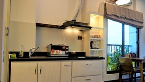 Eine Küche mit weißen Schränken, einer schwarzen Arbeitsplatte, einer Kaffeemaschine und einem Fenster mit Blick.