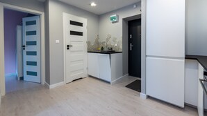 A modern kitchen with white cabinets, a black door, and a tiled backsplash. - Warsaw Concierge Silver Apartment (Warsaw)