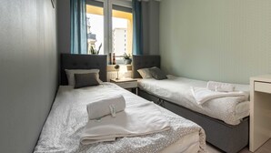 A hotel room with two beds, a small bedside table, a lamp, and a window with curtains. - Warsaw Concierge Silver Apartment (Warsaw)