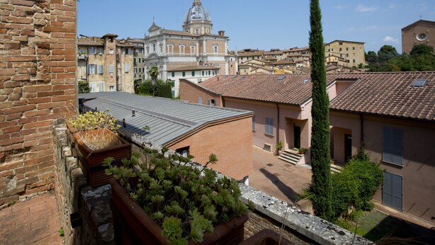 A view of a historic building with a dome, surrounded by traditional European architecture. - Palazzo Piccolomini (Siena)