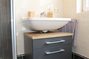 A bathroom with a sink, wooden countertop, two drawers, and a towel hanging on the wall.