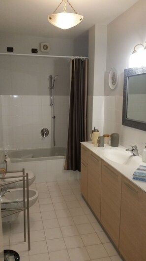 Een bad/douchecombinatie, een haardroger, een bidet, handdoeken