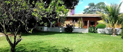 A house with a well-maintained lawn, a small tree, and a palm tree.