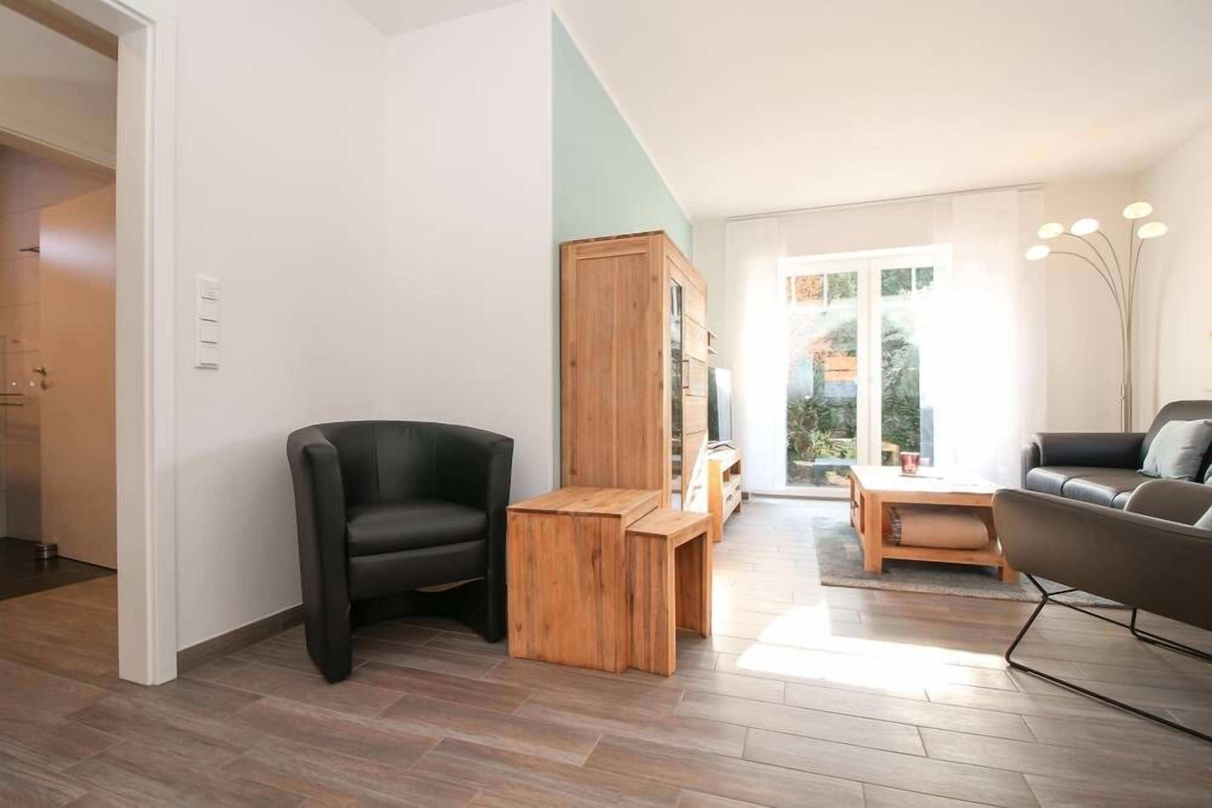 Een moderne woonkamer met een zwarte leren bank, een houten salontafel en een houten kast.