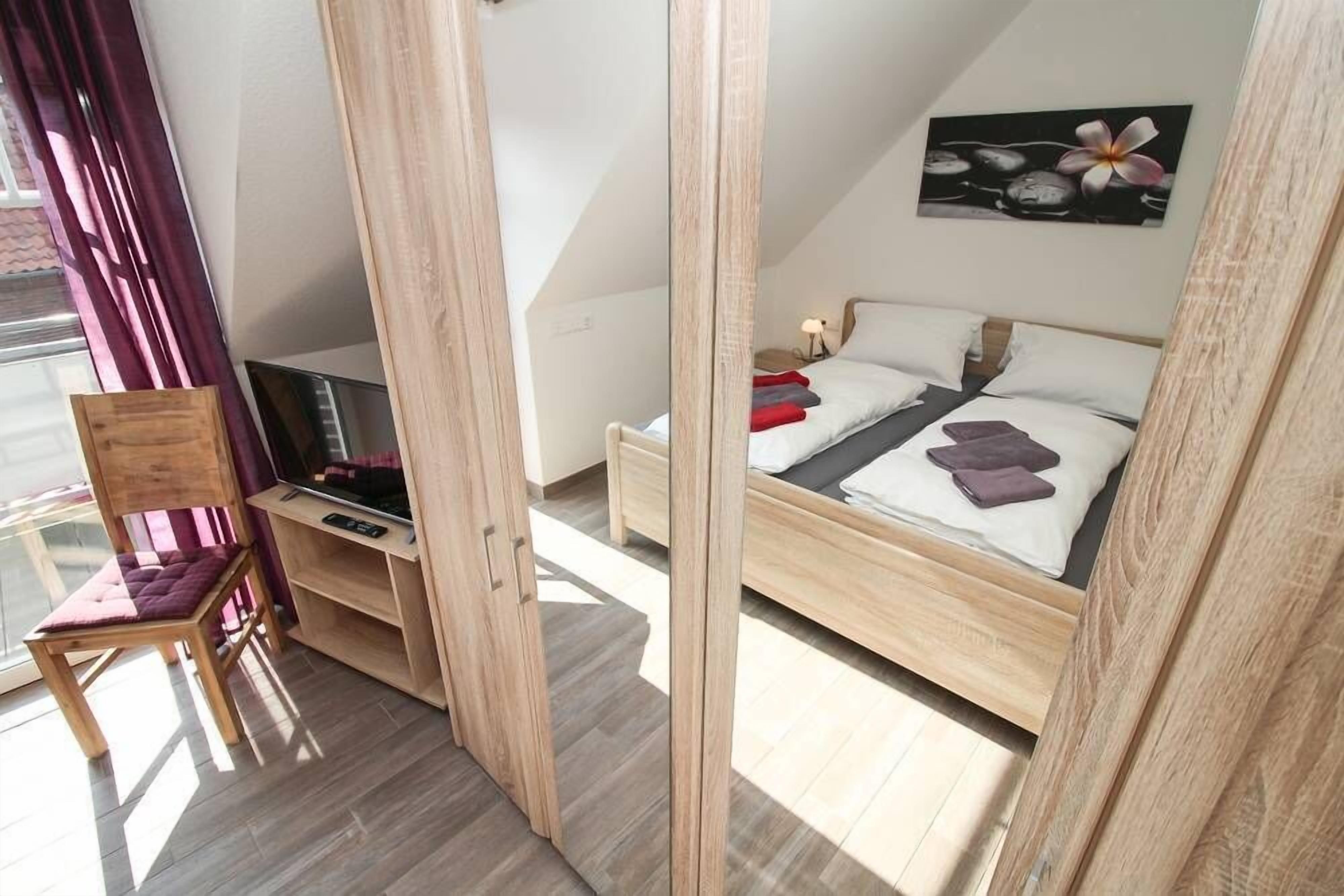 Un dormitorio con una cama, una silla, un escritorio y un televisor.