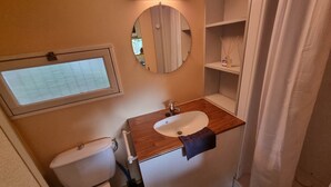 Une salle de bain avec des toilettes, un lavabo, un miroir et une fenêtre.