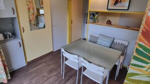 Une cuisine compacte comprenant une table et des chaises, un petit réfrigérateur et un miroir.