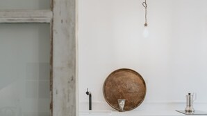 A white cabinet with a round metal plate, a small silver pitcher, and a hanging light fixture. - Warsaw Concierge Unique Design Studio (Warsaw)