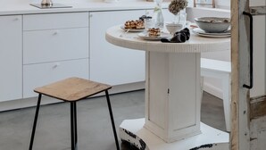 A minimalist kitchen with a white countertop, a wooden stool, and a hanging light fixture. - Warsaw Concierge Unique Design Studio (Warsaw)
