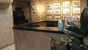 Una recepción con mostrador de madera, un reloj y cuadros en la pared.