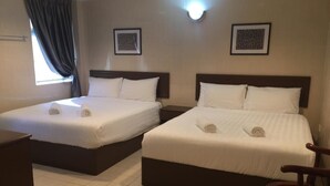 Dos camas individuales con sábanas blancas y cabeceros oscuros en una habitación de hotel.