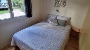 Un dormitorio con cama, ventana, lámpara de techo y decoración en la pared.