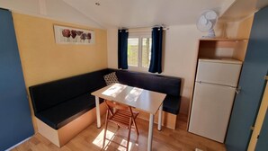 Una cocina compacta con comedor, refrigerador y ventana con cortinas.