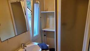 Un baño con un lavamanos blanco, un espejo y una ventana.