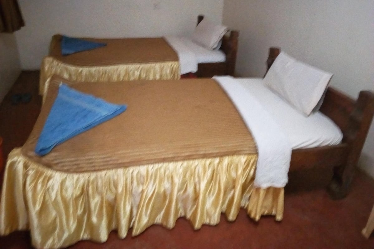 Two single beds with wooden frames and a beige bedspread.