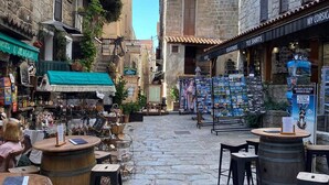 A cobblestone street with outdoor seating, stone buildings, and various shops.